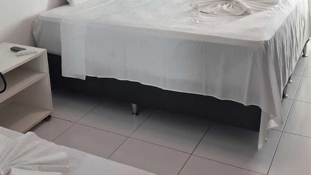 Una camera d'albergo con un letto, un comodino e un tavolino.