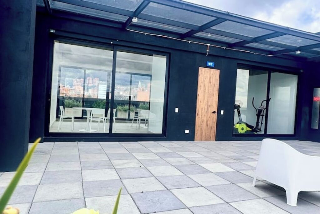 A modern building with large glass windows, a wooden door, and a white bench.