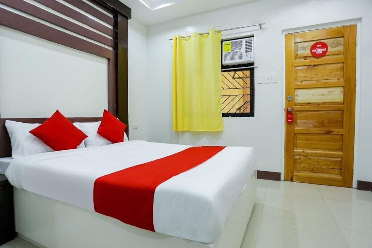 Ein Hotelzimmer mit einem Bett, einer Holztür und einem Fenster mit Vorhang.