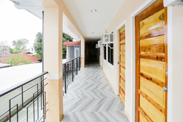 A corridor with a herringbone floor, wooden doors, and a balcony with a railing. - JRJA Suites II Mirafuentes St. Tagum (Tagum)