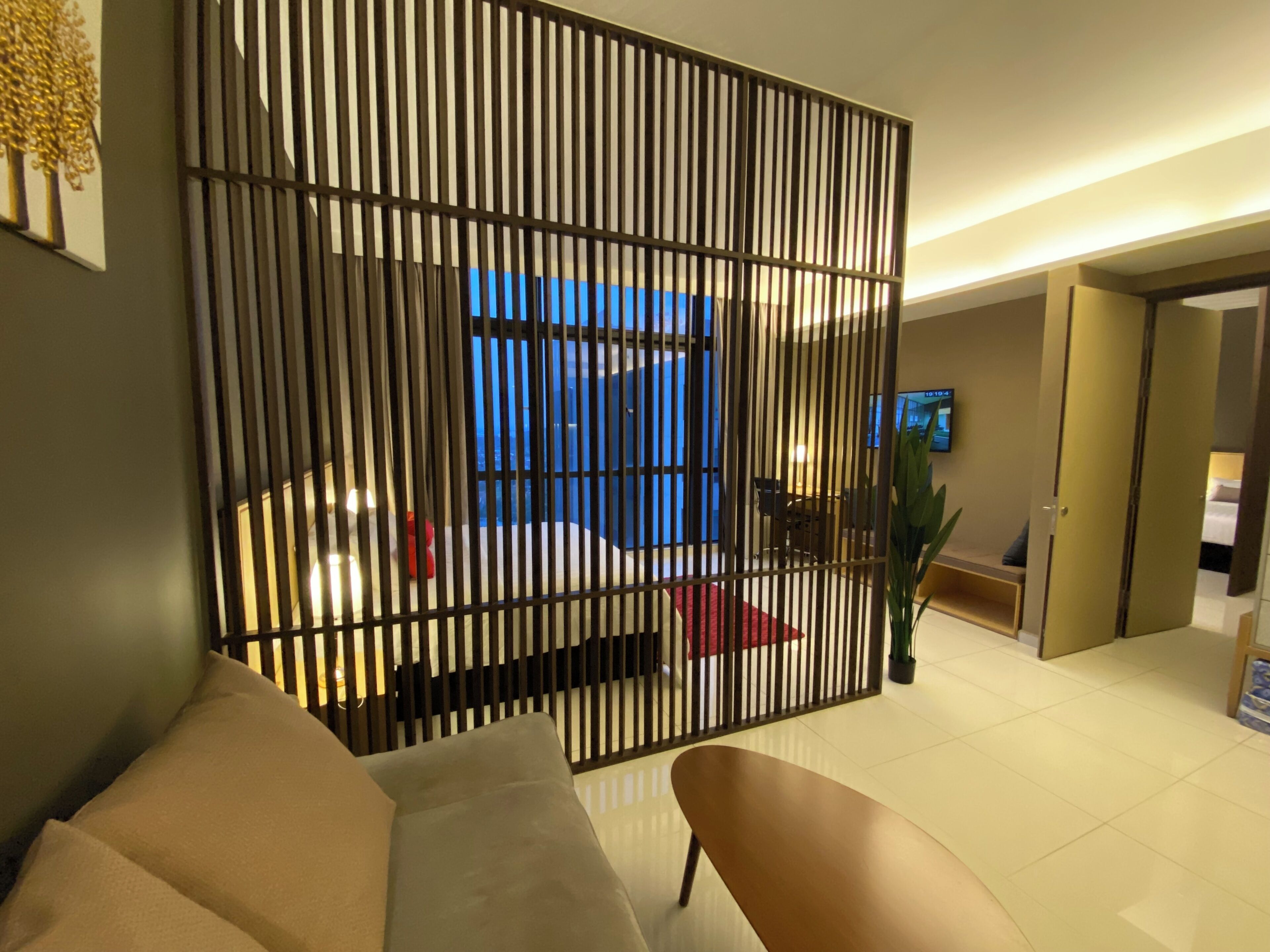 A modern living room with a sofa, a TV, and a decorative partition.