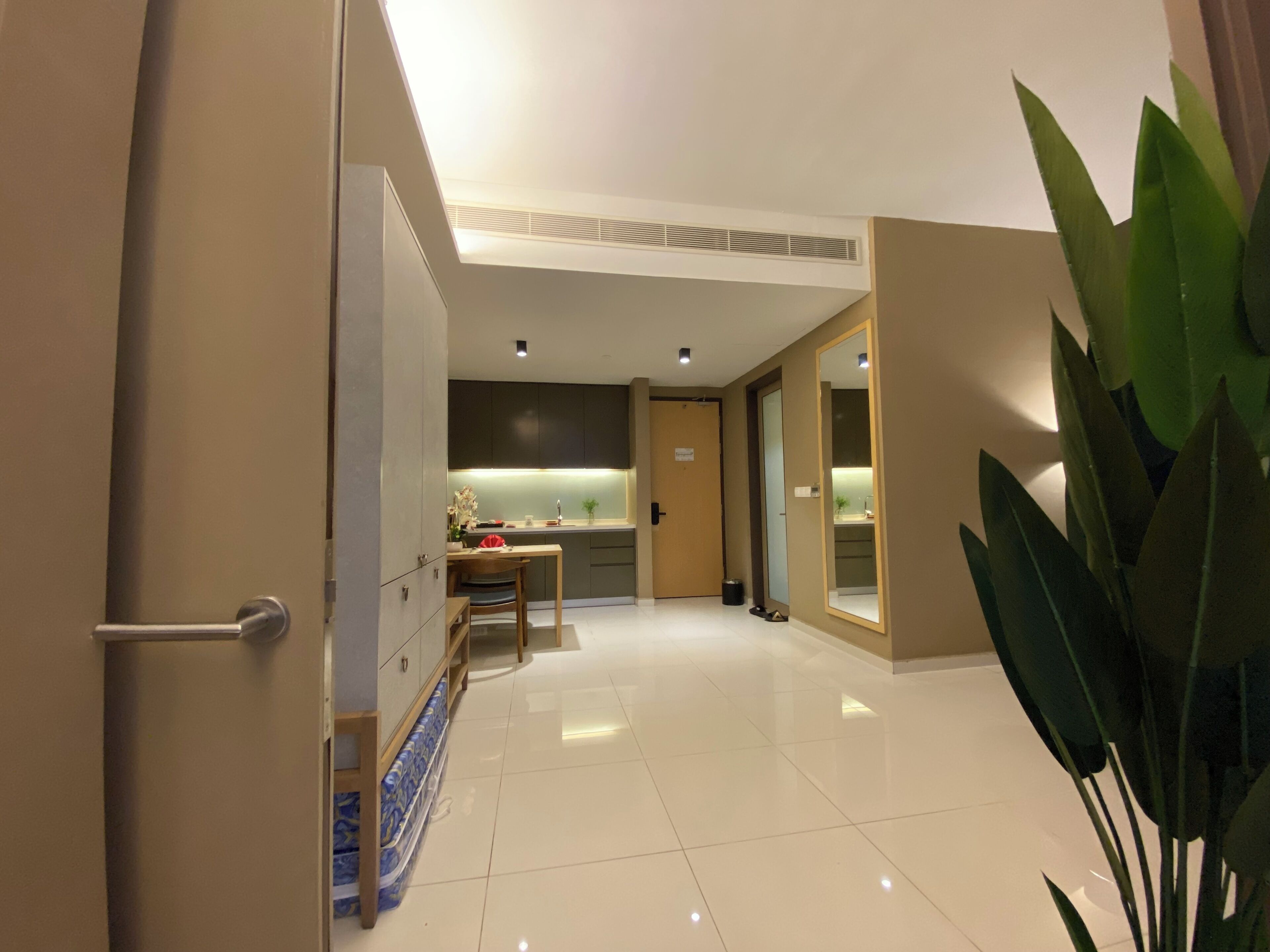 A modern hotel lobby with a clean, minimalist design, featuring a reception desk, a seating area, and a large mirror reflecting the space.