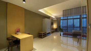 A modern hotel room with a dining area, a bed, a desk, and a large window with blinds.