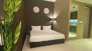 Een moderne slaapkamer met een groot bed, een nachtkastje, een wandlamp en een plant in een pot.