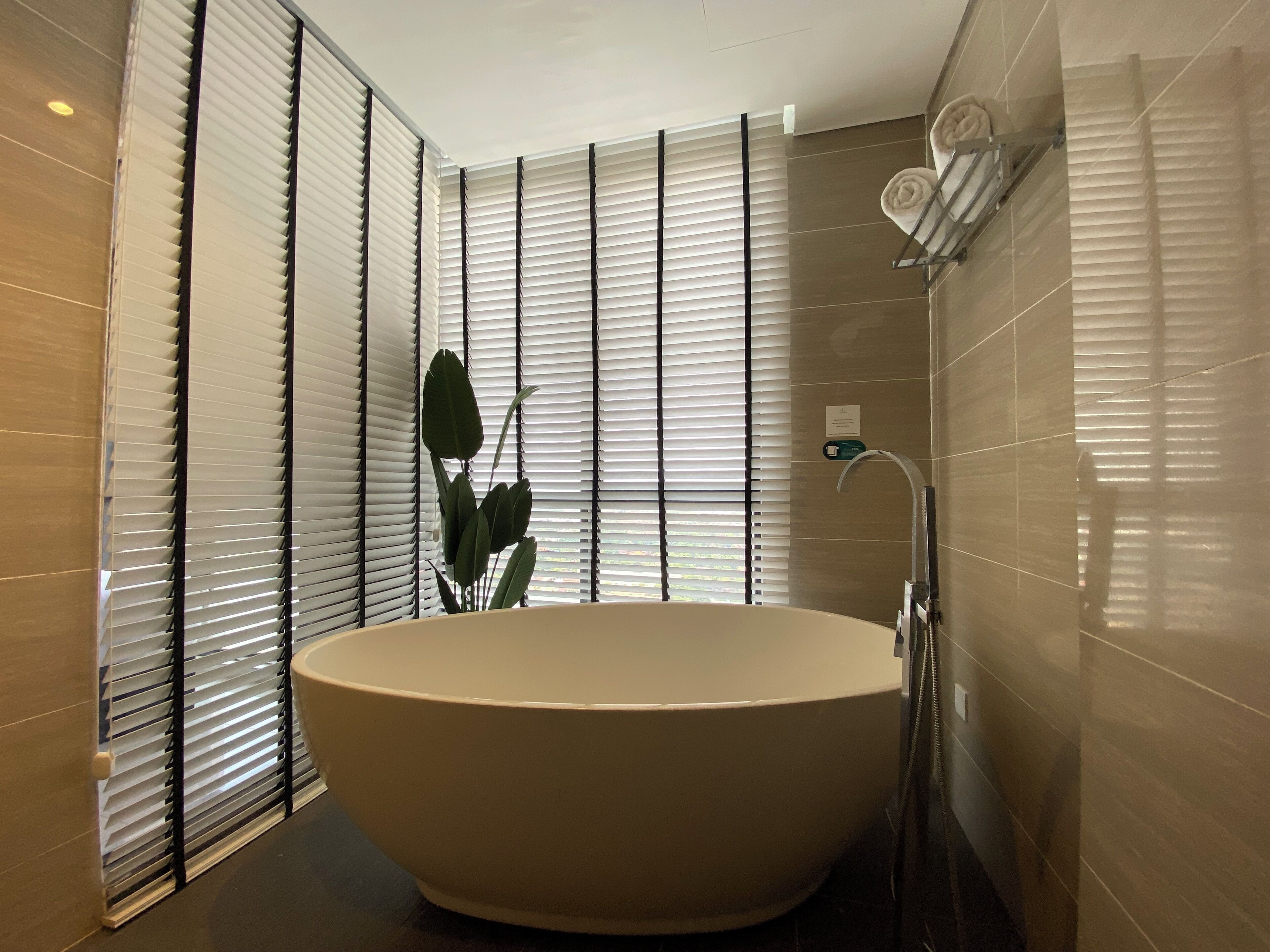 A modern bathroom with a freestanding bathtub, a towel rack, and a potted plant.