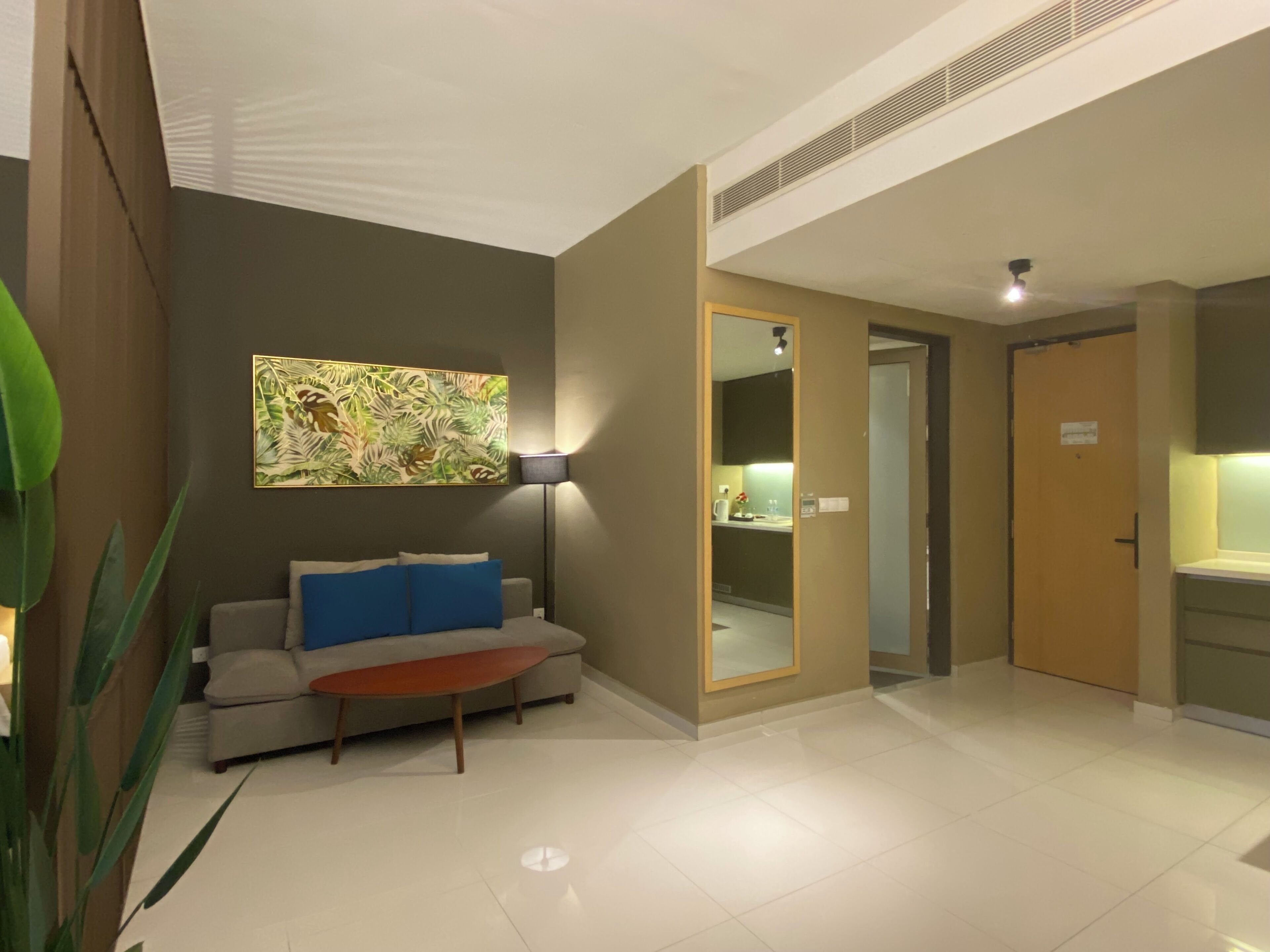 Una habitación de hotel moderna con sofá, una mesa de centro, un cuadro y un espejo.