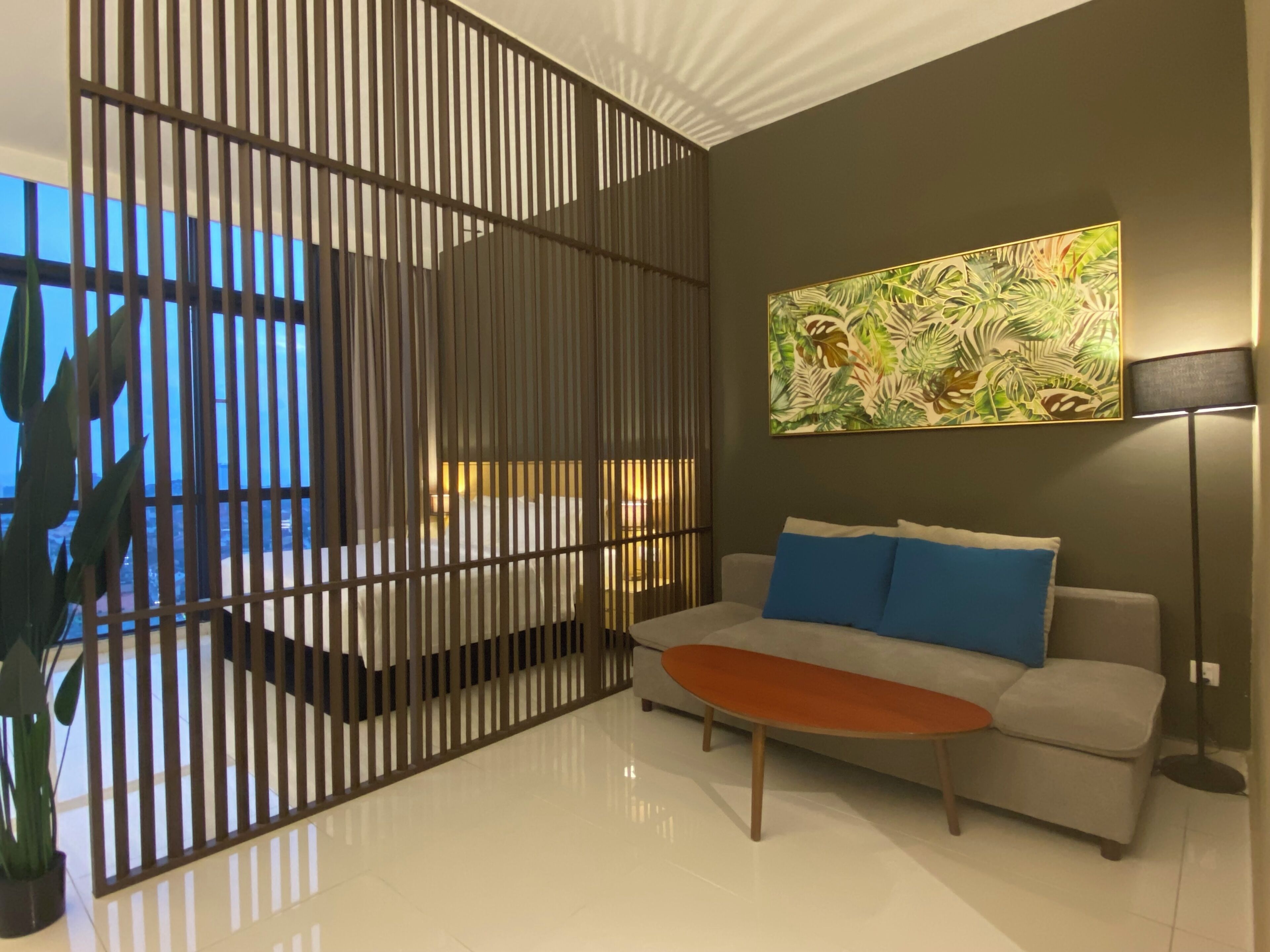 A modern living room with a sofa, a coffee table, a decorative screen, and a painting on the wall.