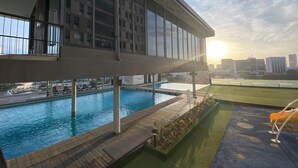 Ein Pool auf dem Dach mit Blick auf die Skyline der Stadt, umgeben von einem modernen Gebäude mit großen Fenstern.