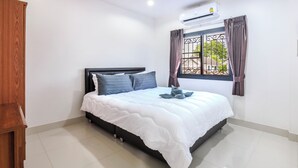 Un dormitorio con cama, armario de madera, ventana con cortinas y equipo de aire acondicionado.