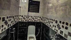 A bathroom with a toilet, a shower, and a wall-mounted heater. - Mantra Inn (Pune)