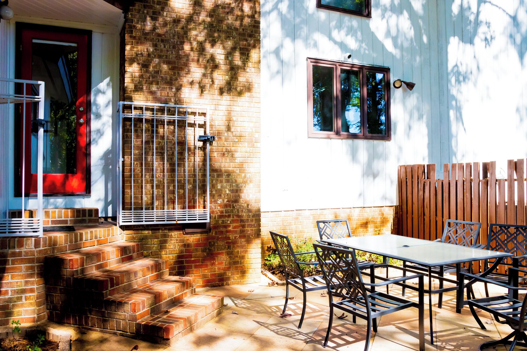 A patio with a table and chairs, a brick wall, and a wooden fence.