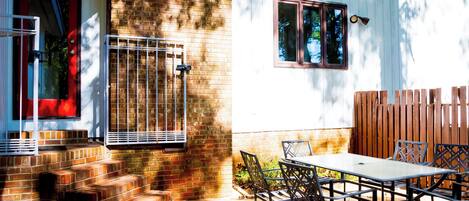 A patio with a table and chairs, a brick wall, and a wooden fence.