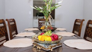 Una mesa de comedor con un centro de flores, un frutero y posavasos.