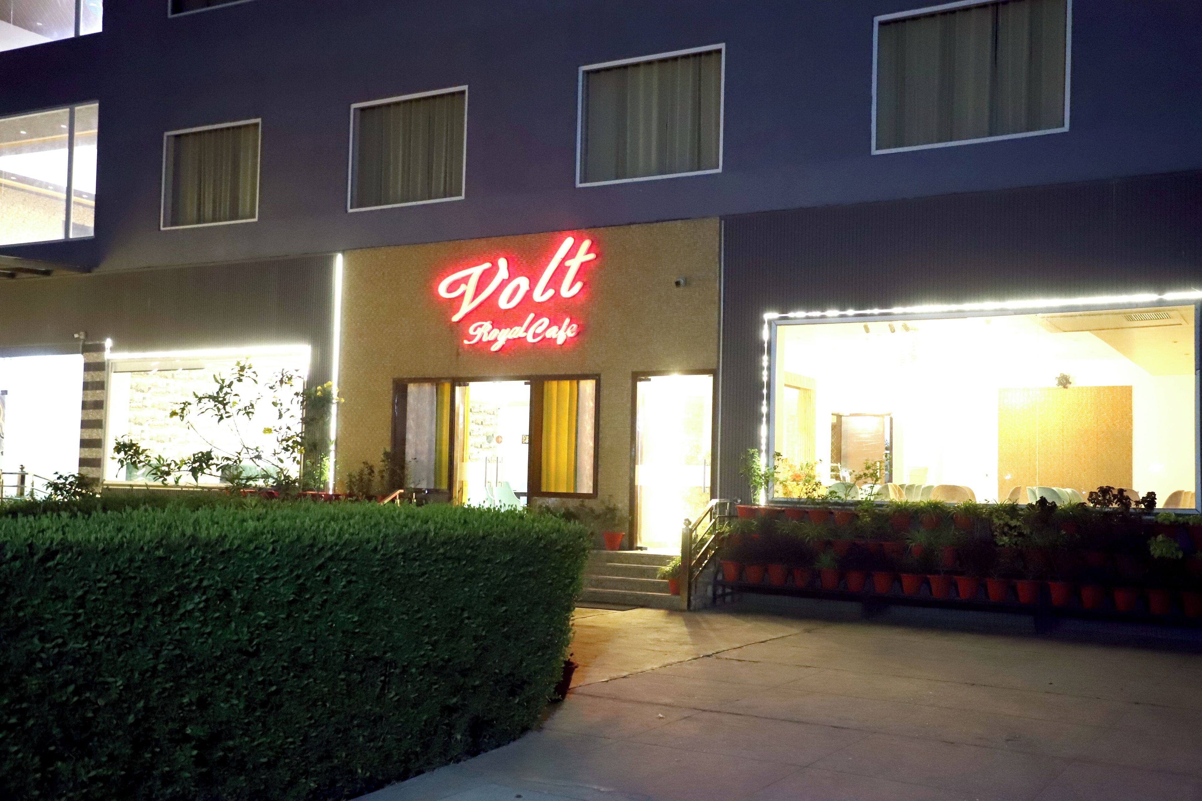 A building with a neon sign reading "Volt Royal Cafe" and a well-lit entrance.