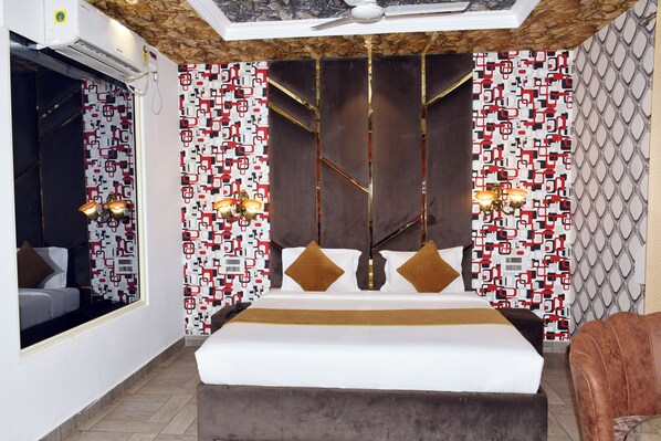 A modern hotel room with a large bed, patterned wallpaper, and a ceiling fan. -  Bellazio Suites Hotel and Resort Bellazio (Bareilly)