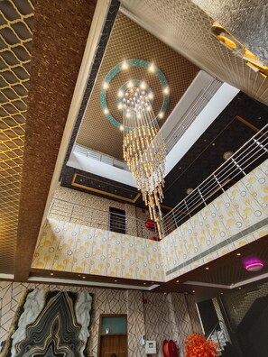 A multi-level atrium with a central chandelier, patterned walls, and a staircase. -  Bellazio Suites Hotel and Resort Bellazio (Bareilly)