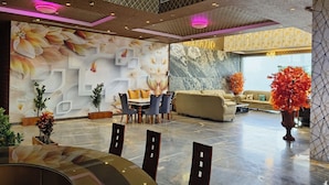 A modern interior with a dining area, sofas, and decorative plants. -  Bellazio Suites Hotel and Resort Bellazio (Bareilly)
