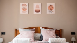 Un letto rifatto con cura, con una testiera in legno, numerosi cuscini e due lampade ai comodini.
