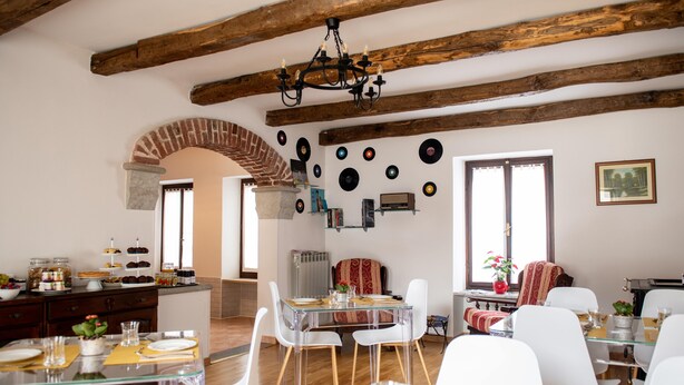 Zona pranzo con soffitto in legno rustico, tavoli in vetro trasparente e sedie bianche.