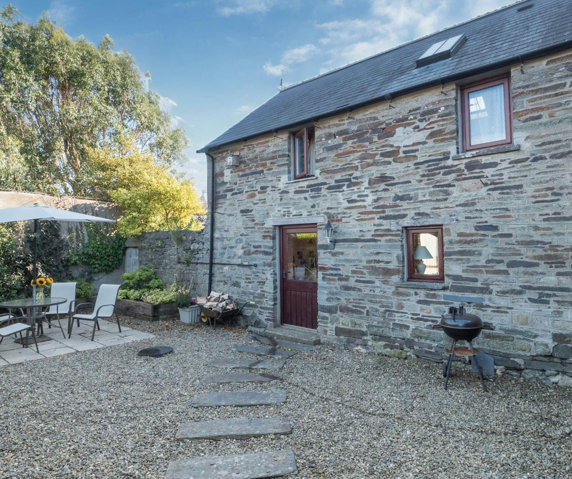 A stone house with a gravel patio, a wooden door, and a small window.