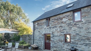 A stone house with a gravel patio, a wooden door, and a small window. - Y Cartws, Cardigan - Two Bedroom Cottage, Sleeps 4 (Cardigan)
