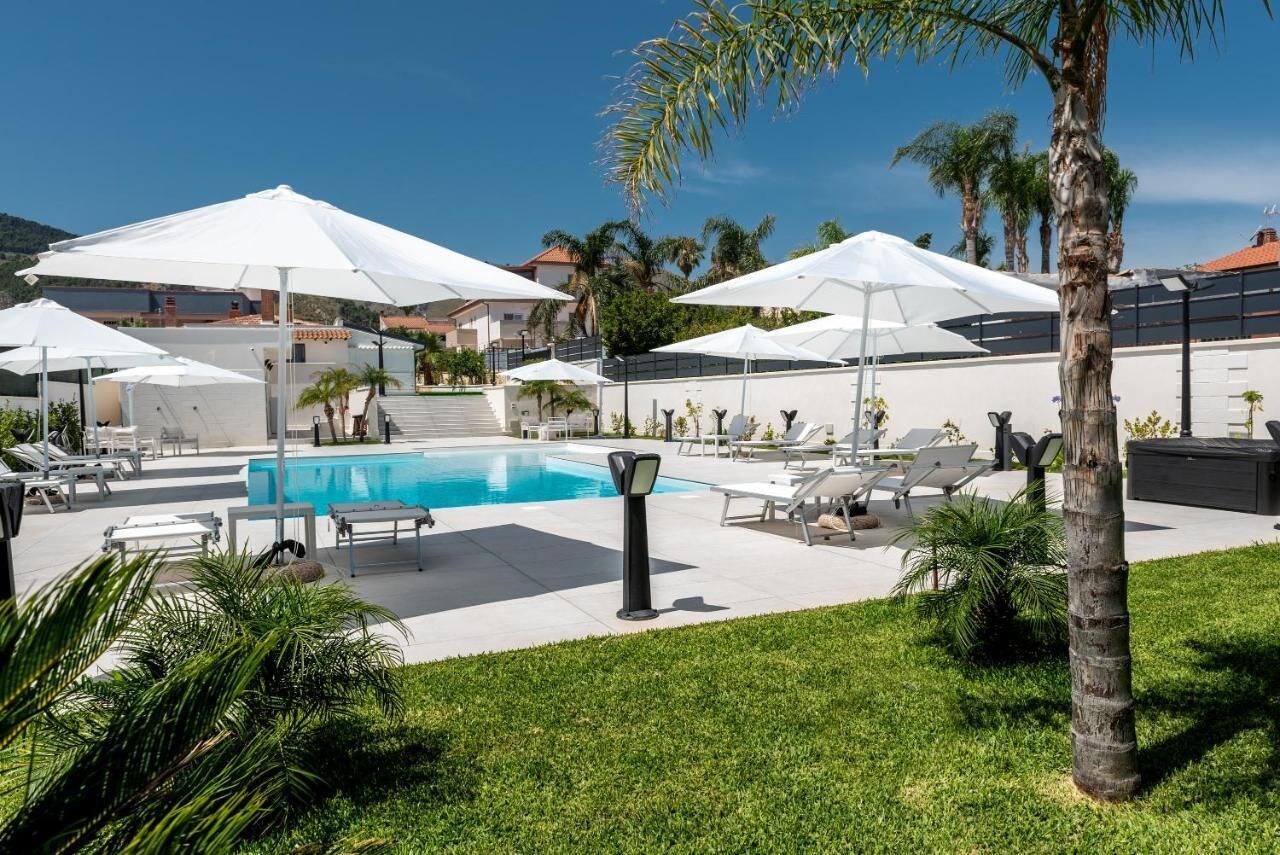Un espace piscine agrémenté de parasols blancs, de chaises longues et d’une piscine à l’eau d’un bleu limpide.