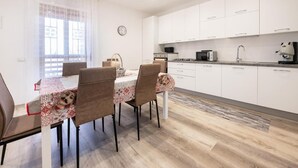 A modern kitchen with white cabinets, a dining table with chairs, and a clock on the wall.