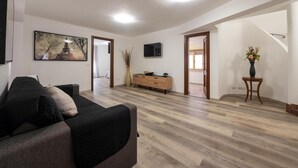 A modern living room with a sofa, a TV, a wooden cabinet, and a staircase leading to another room.