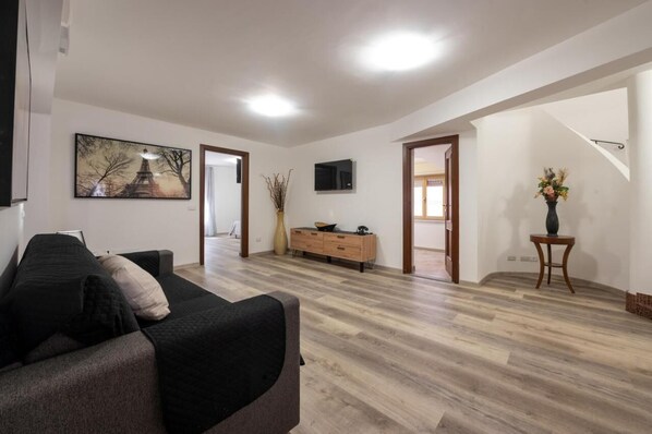 Un salon moderne avec un canapé, un téléviseur, un meuble en bois et un escalier menant à une autre pièce.