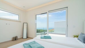A modern bedroom with two beds, large windows, and a view of the landscape. - Villa Atlantica One luxury and unique with ocean view (Lourinha)