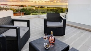 A rooftop terrace with wicker furniture, a bottle of wine, and glasses. - Villa Atlantica One luxury and unique with ocean view (Lourinha)