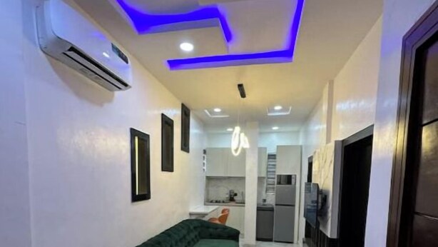 A narrow hallway with a green sofa, a small trash bin, and a door on the right. - Classic 2bedroom Flat in GRA

 (Ikeja)