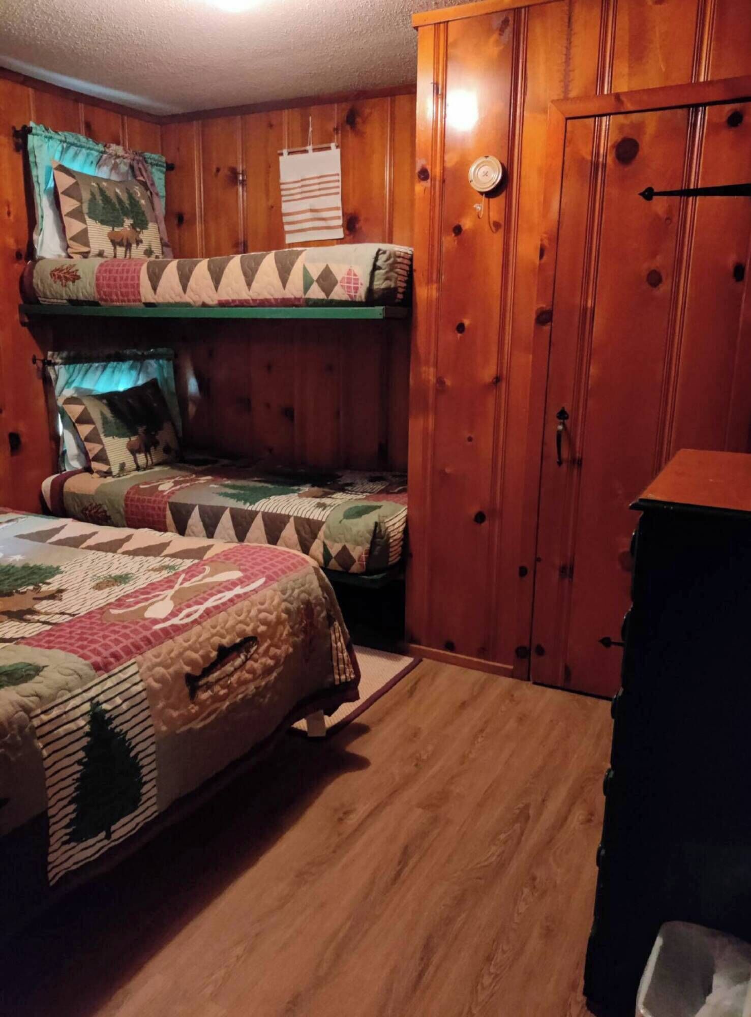 Ein schlicht eingerichtetes Schlafzimmer im Chalet-Stil mit zwei Etagenbetten, Holzwänden, einem Kleiderschrank und einem kleinen Tisch.