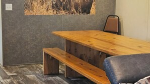 A room with a wooden dining table, benches, a blue sofa, and a wall-mounted moose picture. - Classy 3 Bed home w/ pool access - Moose Cabin (Elizabeth)
