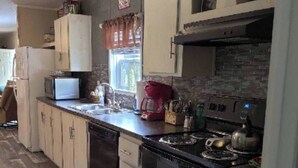 A kitchen with a black stove, white cabinets, a microwave, and a red coffee maker. - Classy 3 Bed home w/ pool access - Moose Cabin (Elizabeth)