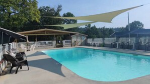 A swimming pool with lounge chairs and a shaded area. - Entire Cabin on Norfork Lake with swimming pool (Elizabeth)