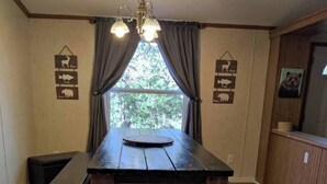 A wooden dining table with benches, a chandelier, and curtains. - Entire Cabin on Norfork Lake with swimming pool (Elizabeth)