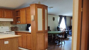 A kitchen with wooden cabinets and a dining area with a table and chairs. - Entire Cabin on Norfork Lake with swimming pool (Elizabeth)