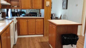 A compact kitchen with wooden cabinets, a stove, and a trash bin. - Entire Cabin on Norfork Lake with swimming pool (Elizabeth)