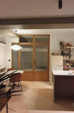 Enjoy meals at the dining table in this kitchen with cabinet and refrigerator.