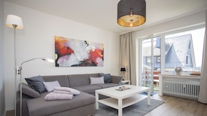 A modern living room with a grey sofa, white coffee table, and a large abstract painting on the wall. - Appartment - Lenneblick 2 | Altastenberg (Winterberg) (Winterberg)