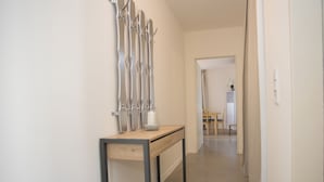 A hallway with a wooden desk and metal frame, a wall-mounted abstract sculpture, and a glimpse of a dining area in the distance. - Appartment - Lenneblick 2 | Altastenberg (Winterberg) (Winterberg)