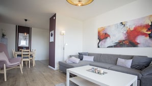 A modern living room with a grey sofa, white coffee table, and a painting on the wall. - Appartment - Lenneblick 2 | Altastenberg (Winterberg) (Winterberg)