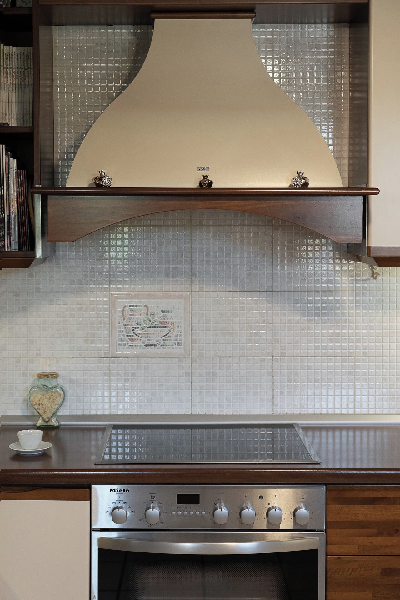A kitchen with a tiled backsplash, a stove, and a small decorative item on the counter.