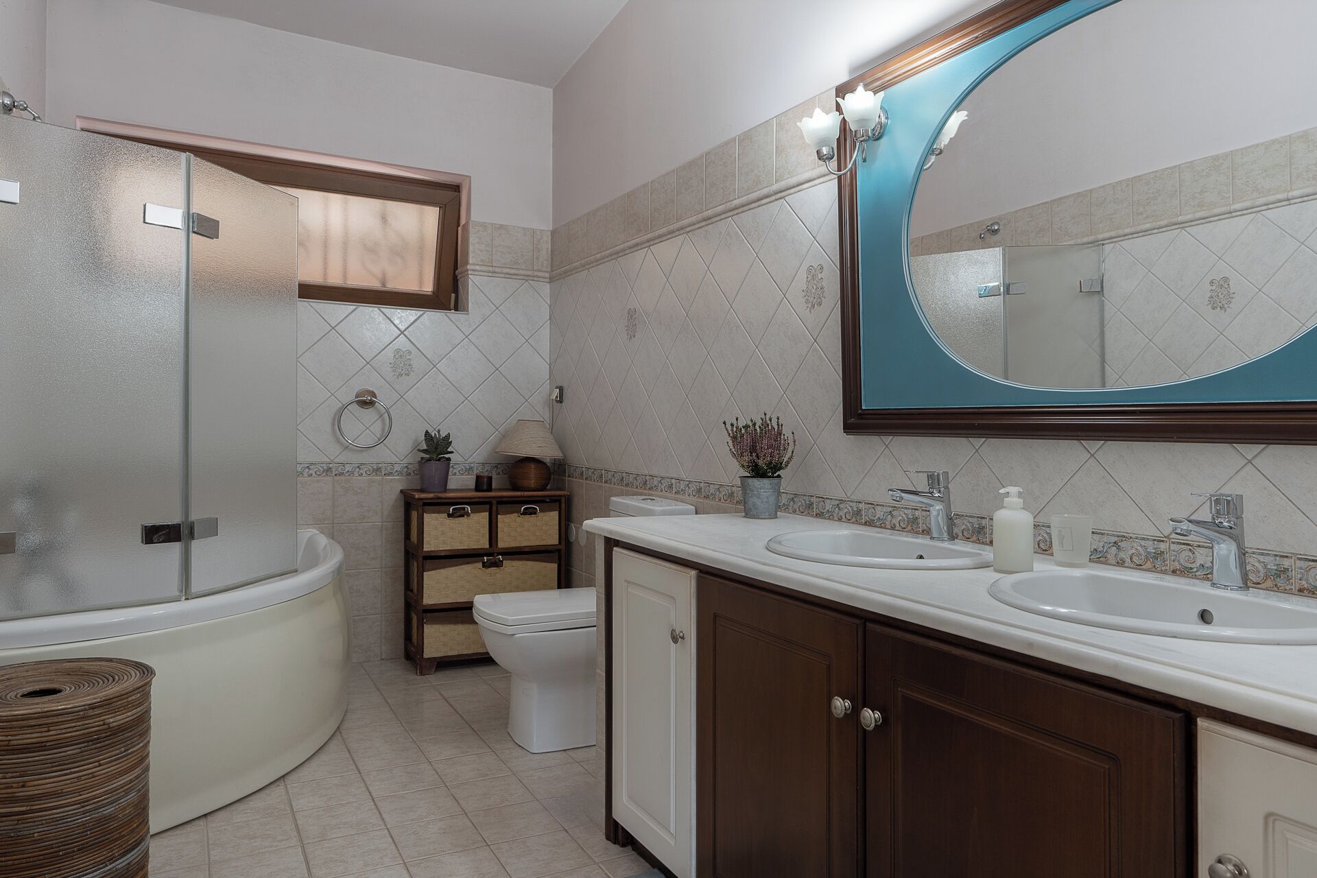 Un bagno moderno con vasca, due lavandini, un water e un mobile lavabo con pensili.