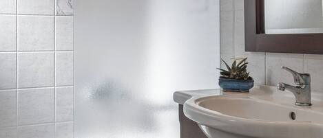 A bathroom with a bathtub, a sink, and a mirror.