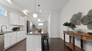 Een moderne keuken met witte kasten, een centraal eiland en hanglampen.