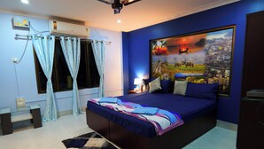 Un dormitorio con una cama grande, un mural de paisaje urbano, un ventilador de techo y una ventana con cortinas.
