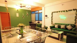 Una sala de estar moderna con un sofá verde, una mesa de centro de vidrio y una mesa de comedor con sillas.