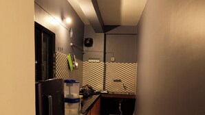 Una cocina estrecha con refrigerador, pileta y salpicadero de azulejos.